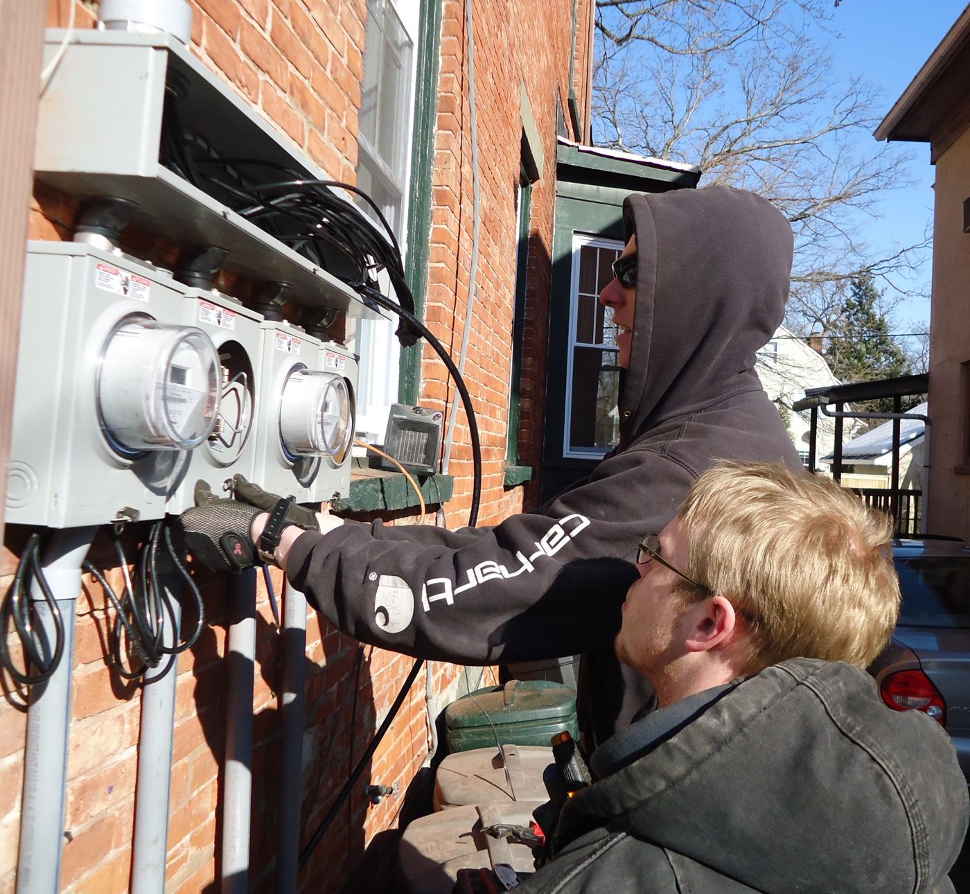 Electricians mounting new meter sockets on a brick wall